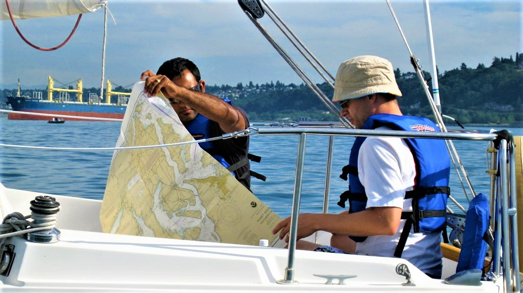 ASA students in the cockpit of a Catalina 25 reading nautical charts outside the Port of Tacoma
