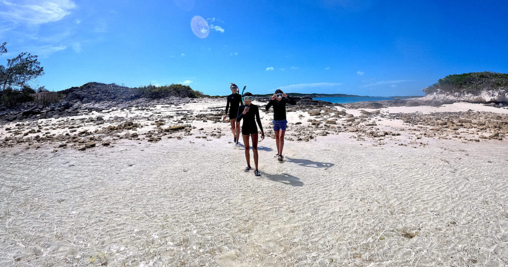 Snorkelers walking on Pirate Trap Beach at Staniel Cay, Bahamas