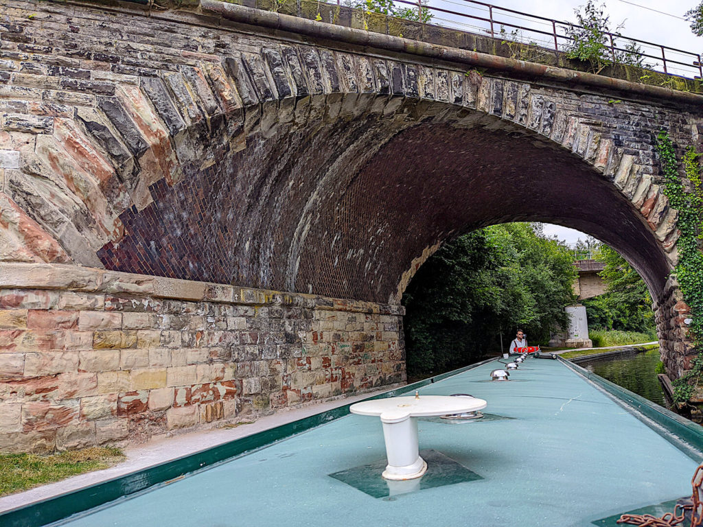 Narrowboat Rental passing beneath a cobble stone bridge along the Trent and Mersey Canal