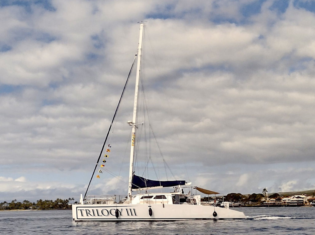 Trilogy sailing catamaran leaving Lahaina HArbor with its sails furled